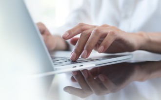 Person tippt auf Laptop